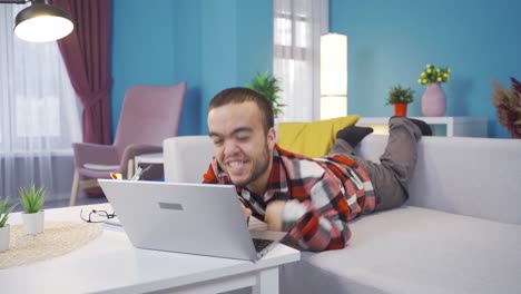 Disabled-dwarf-young-man-happy-and-cheerful-using-laptop,-lying-on-sofa-and-resting.